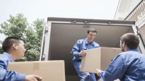 Three movers unloading boxes from moving truck.