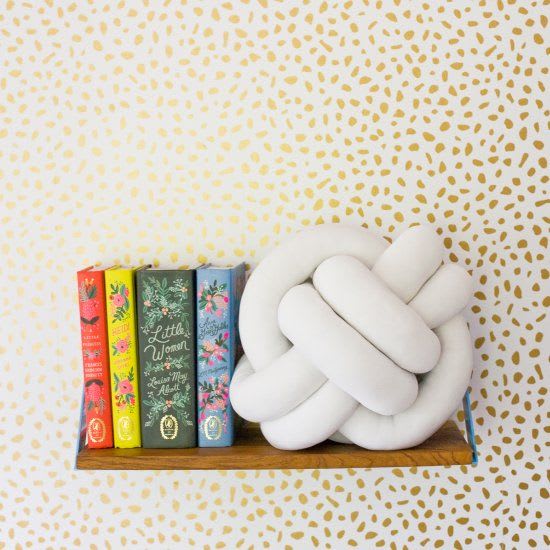 White knot pillow on a floating bookshelf. 