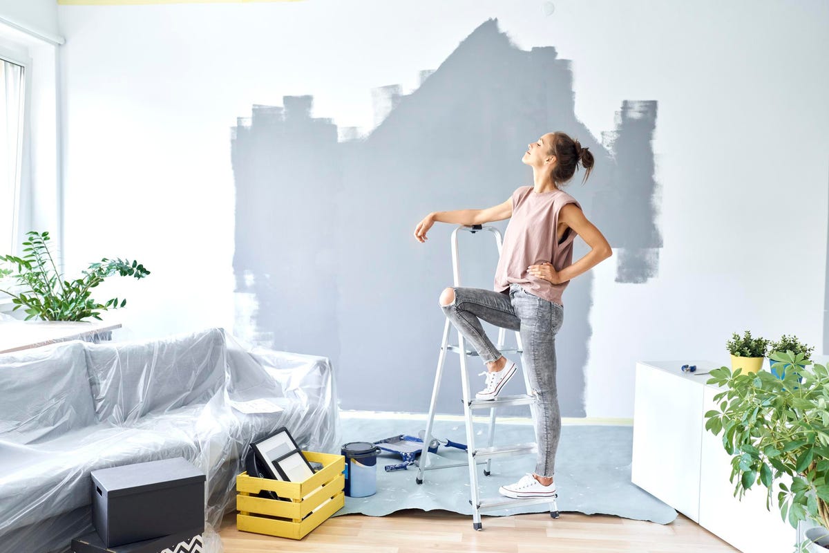 Woman standing against a ladder taking a break from painting her house.