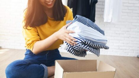 Woman packing clothes into cardboard box.