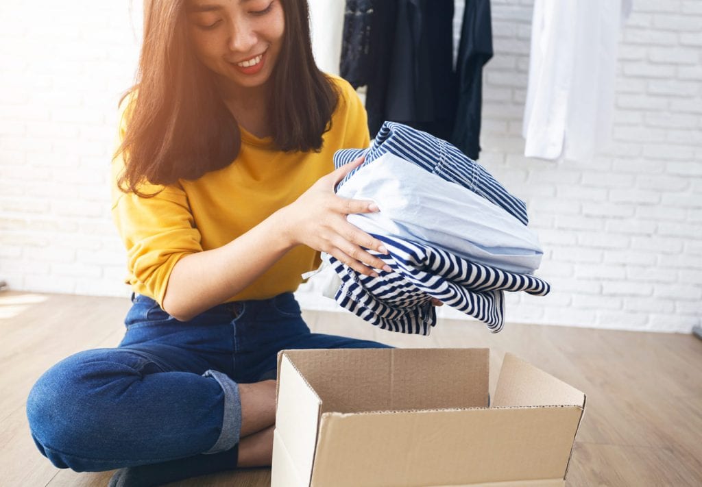 Woman packing clothes into cardboard box.